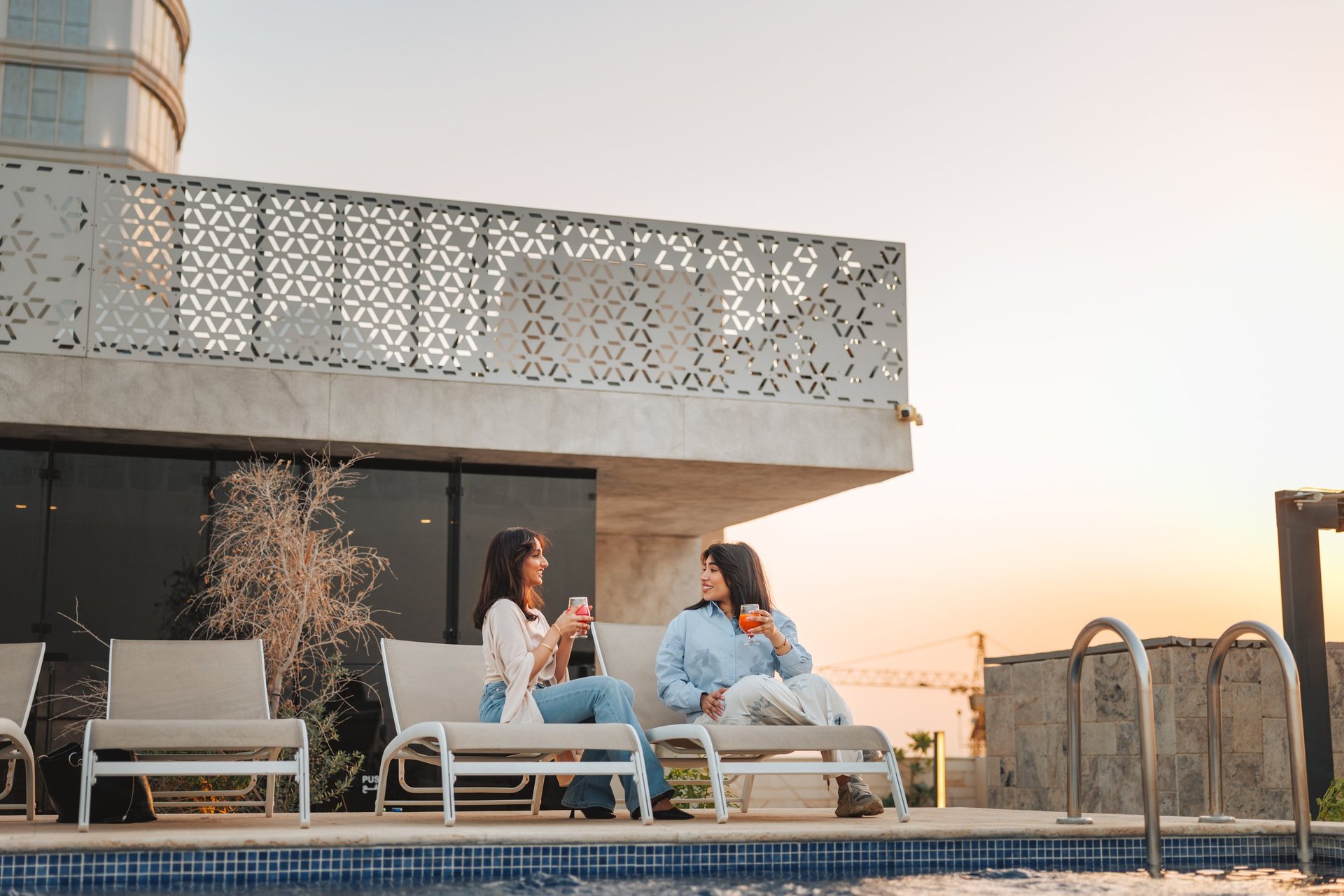 Young women enjoying drinks by the pool on a rooftop terrace