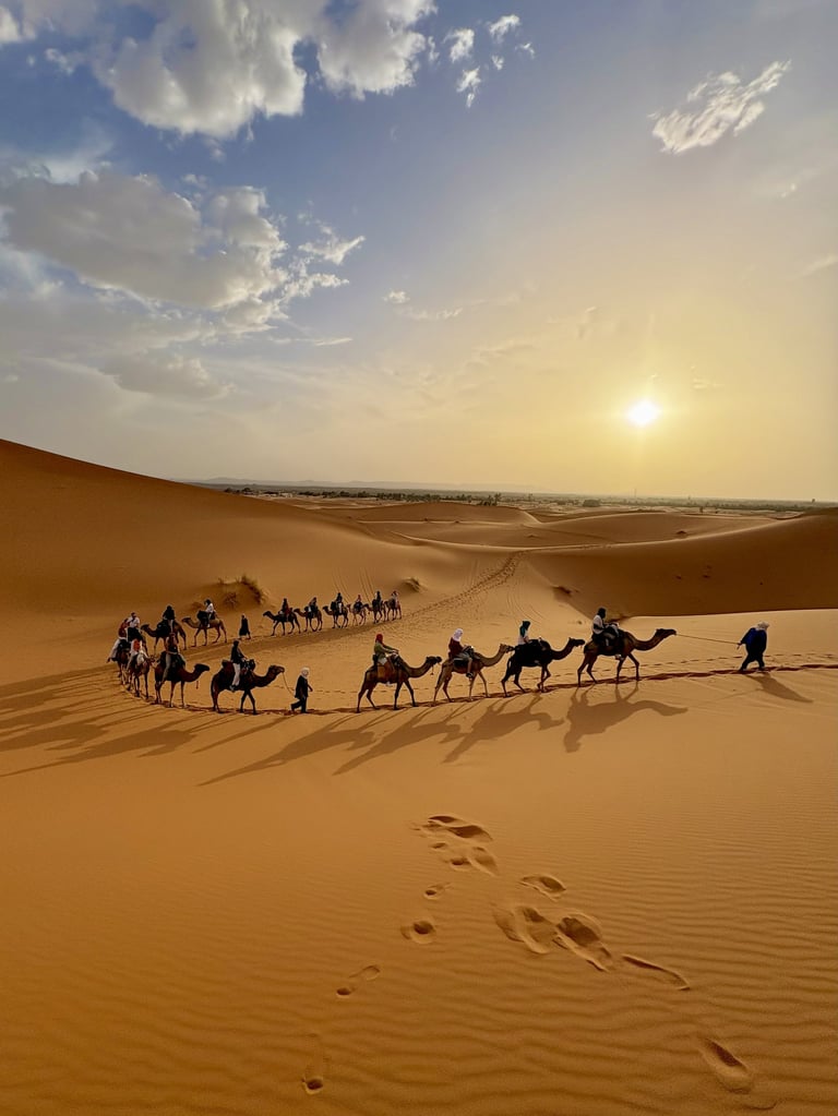 Camel caravan through golden desert dunes at sunset